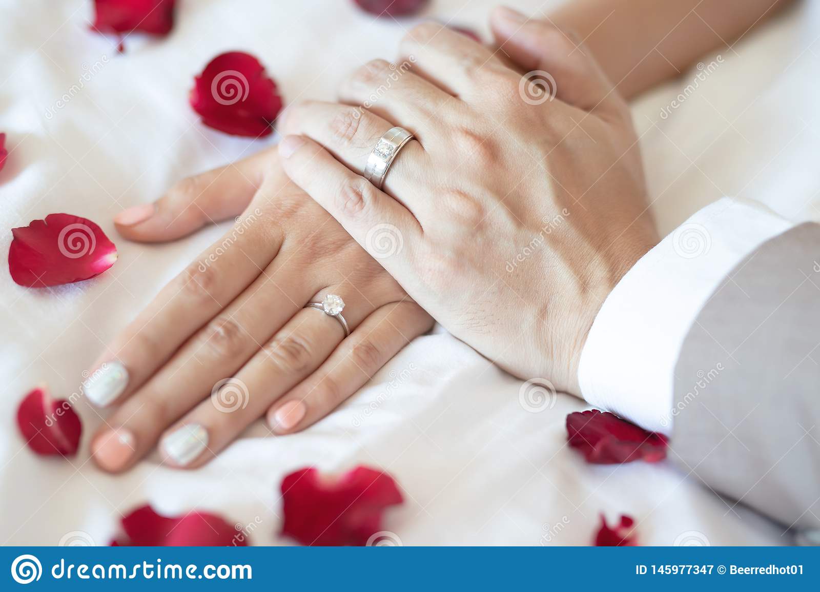 close-up-hand-groom-couple-lovers-show-wear-wedding-ring-bride-holding-hands-together-bed-sprinkle-rose-petals-represents-145977347-9b45312e